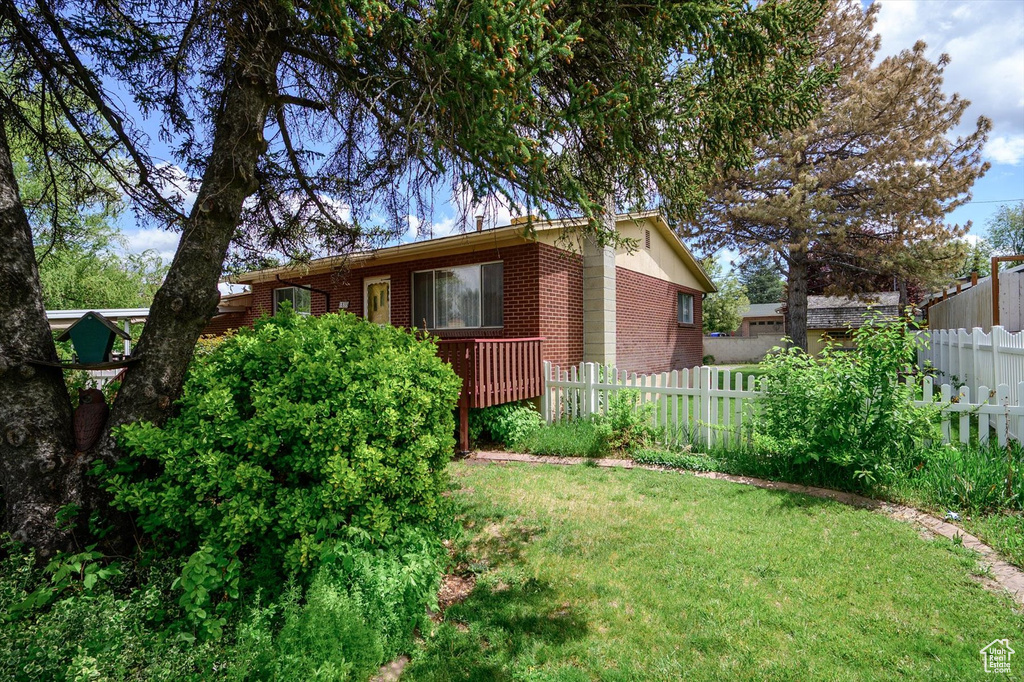 Exterior space with a yard, brick siding, and fence
