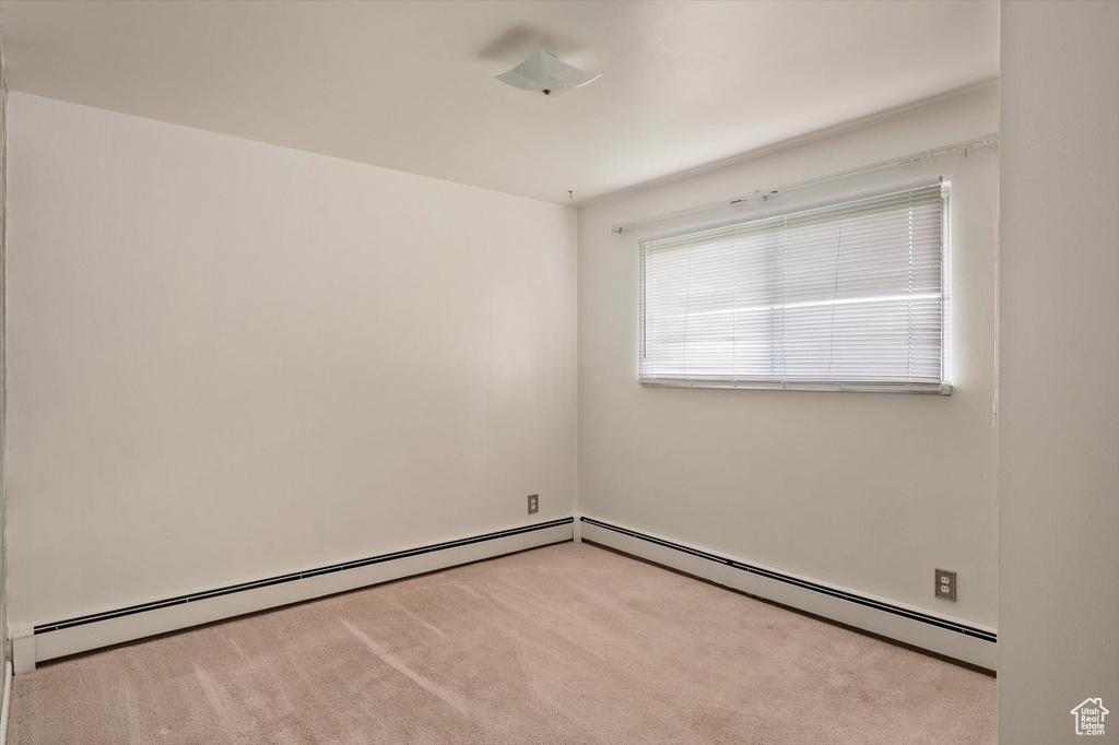 Unfurnished room with carpet and a baseboard heating unit