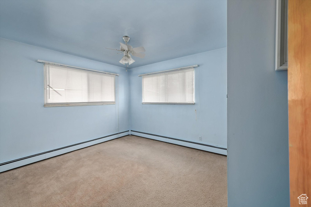 Spare room featuring ceiling fan, carpet, and a baseboard radiator