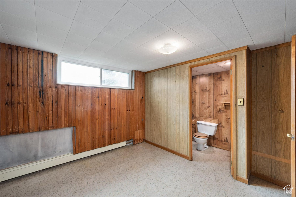 Interior space with tile patterned floors, baseboards, baseboard heating, and wood walls