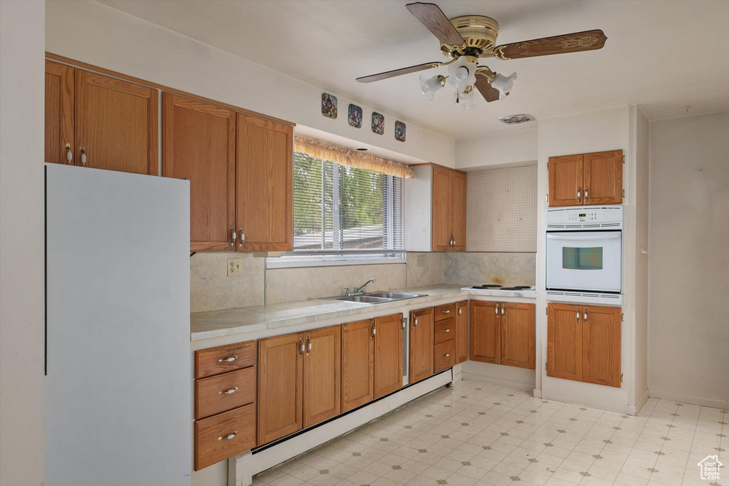 Kitchen featuring tasteful backsplash, a sink, white appliances, tile counters, and light floors