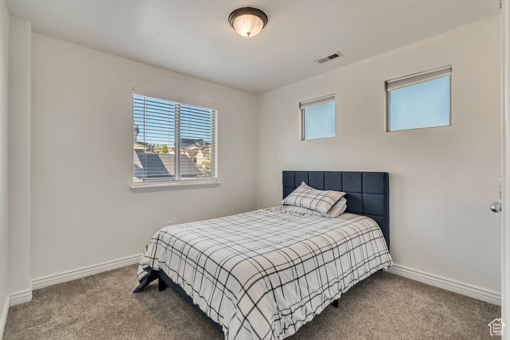 Carpeted bedroom with baseboards and visible vents