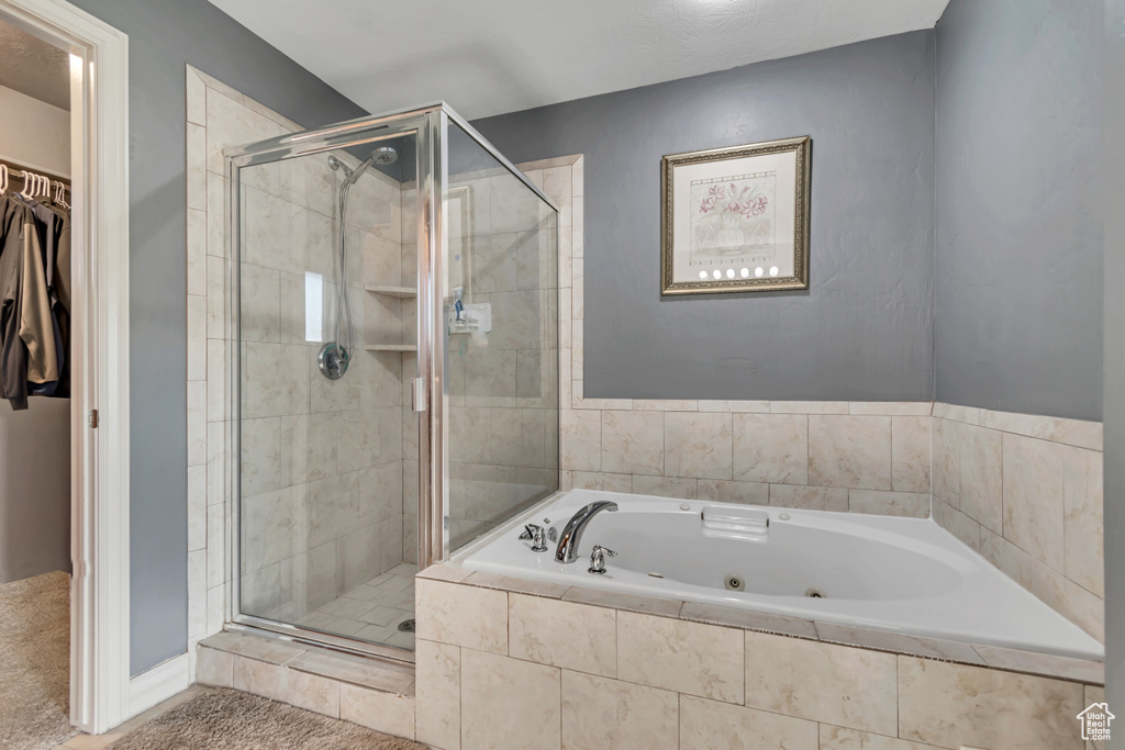 Bathroom with a walk in closet, a stall shower, and a tub with jets