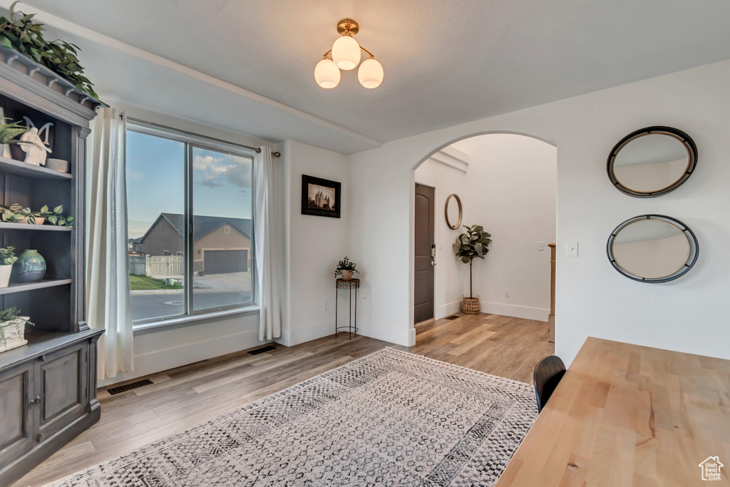 Interior space with visible vents, arched walkways, light wood finished floors, and baseboards
