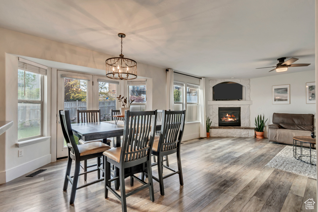 Dining space with light wood-style floors, a healthy amount of sunlight, and a fireplace