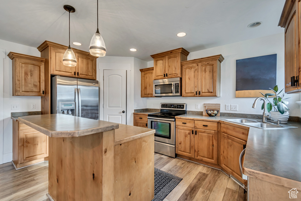Kitchen featuring a kitchen island, a sink, light wood finished floors, stainless steel appliances, and recessed lighting