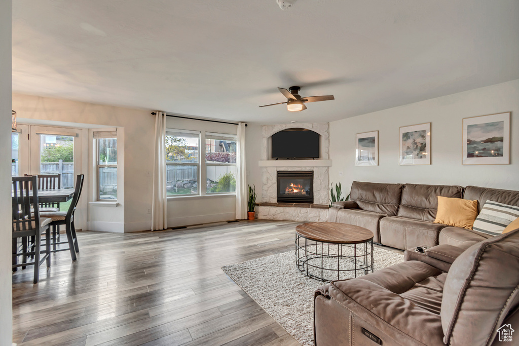Living area with baseboards, ceiling fan, a fireplace, and wood finished floors