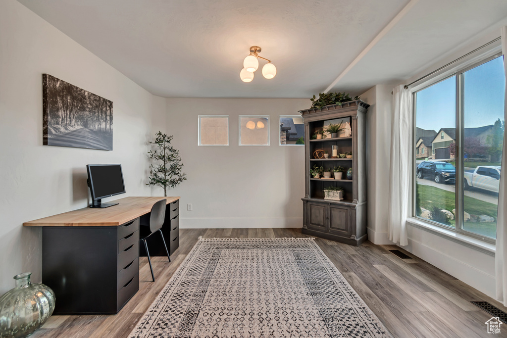 Office area featuring an inviting chandelier, baseboards, light wood-style flooring, and visible vents
