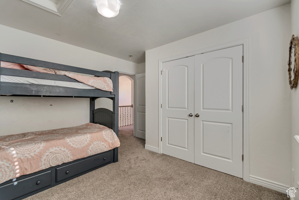 Bedroom featuring baseboards, light carpet, and a closet