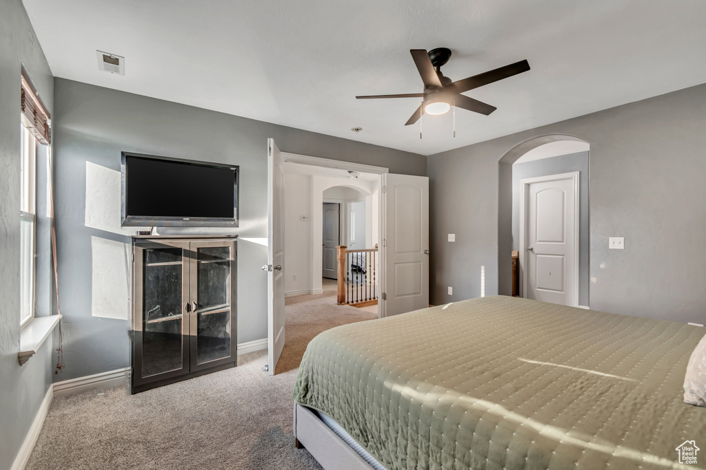 Carpeted bedroom featuring baseboards, arched walkways, and a ceiling fan
