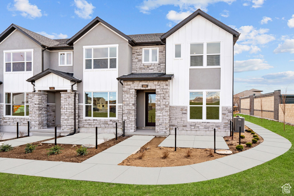 View of front of house with board and batten siding, fence, and stone siding