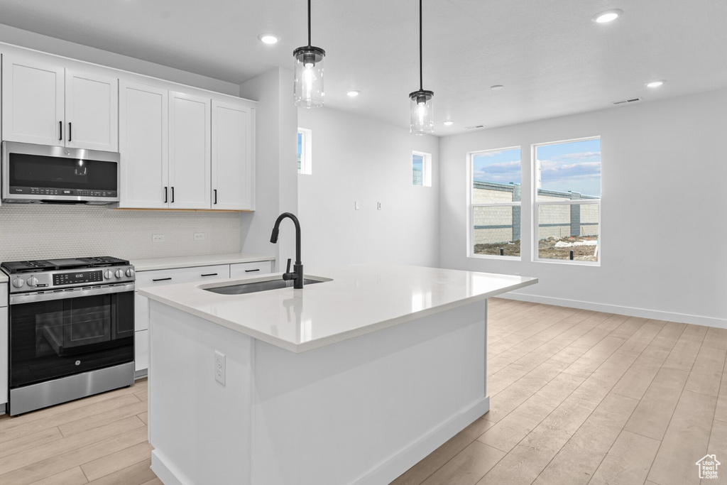 Kitchen featuring a sink, appliances with stainless steel finishes, light wood-style flooring, and light countertops