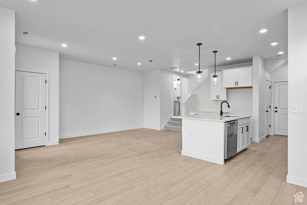 Kitchen with a sink, light countertops, recessed lighting, open floor plan, and stainless steel dishwasher