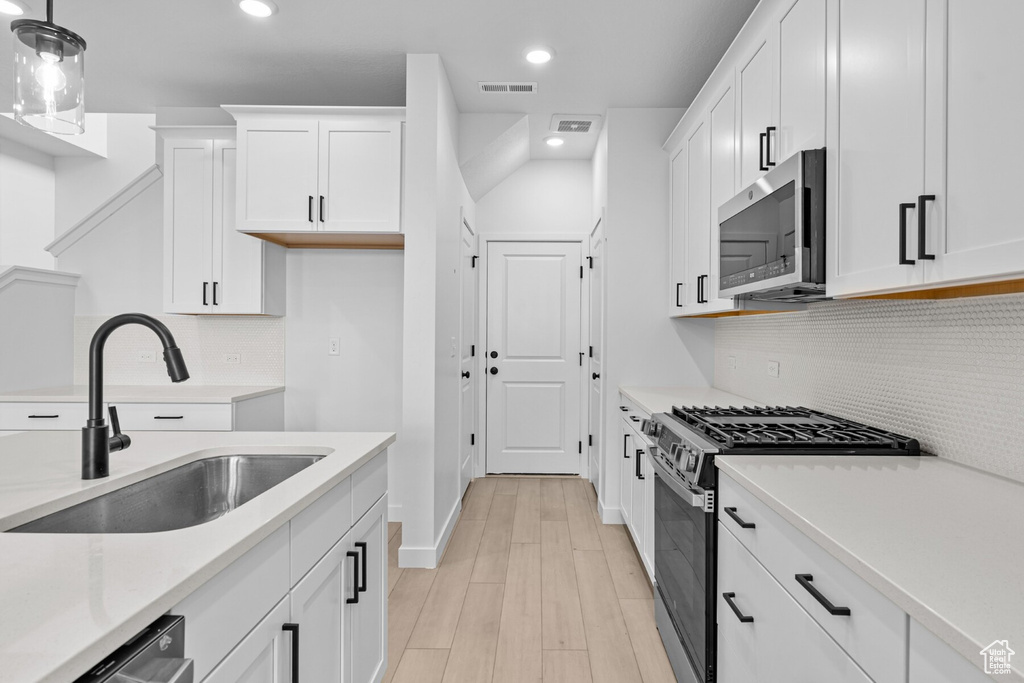 Kitchen featuring visible vents, pendant lighting, a sink, stainless steel appliances, and white cabinetry