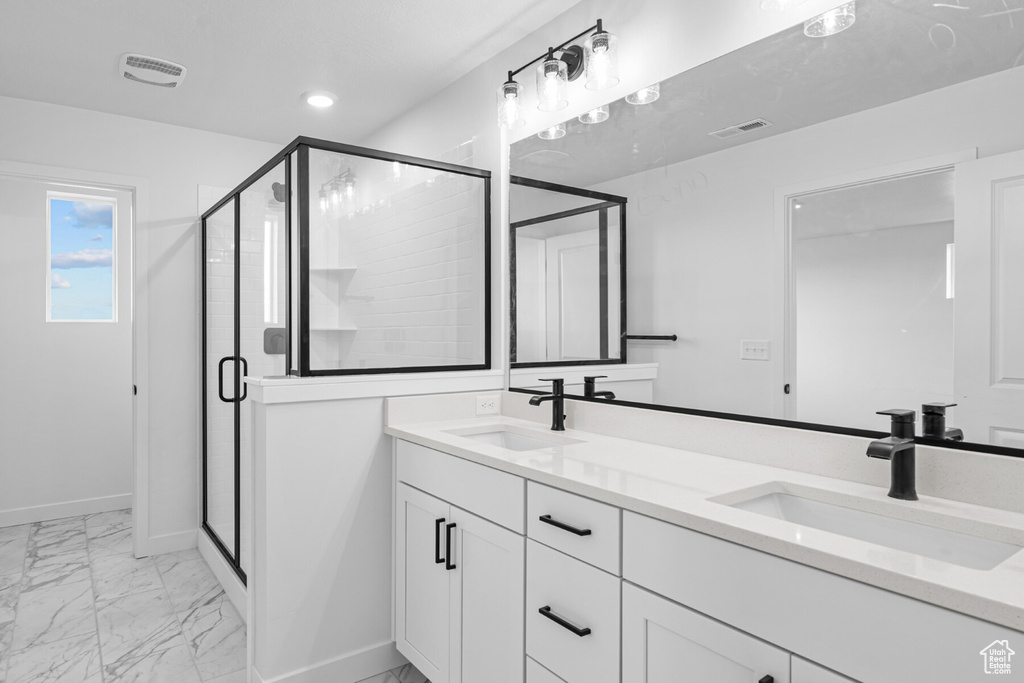 Full bath with double vanity, a sink, marble finish floor, and a stall shower