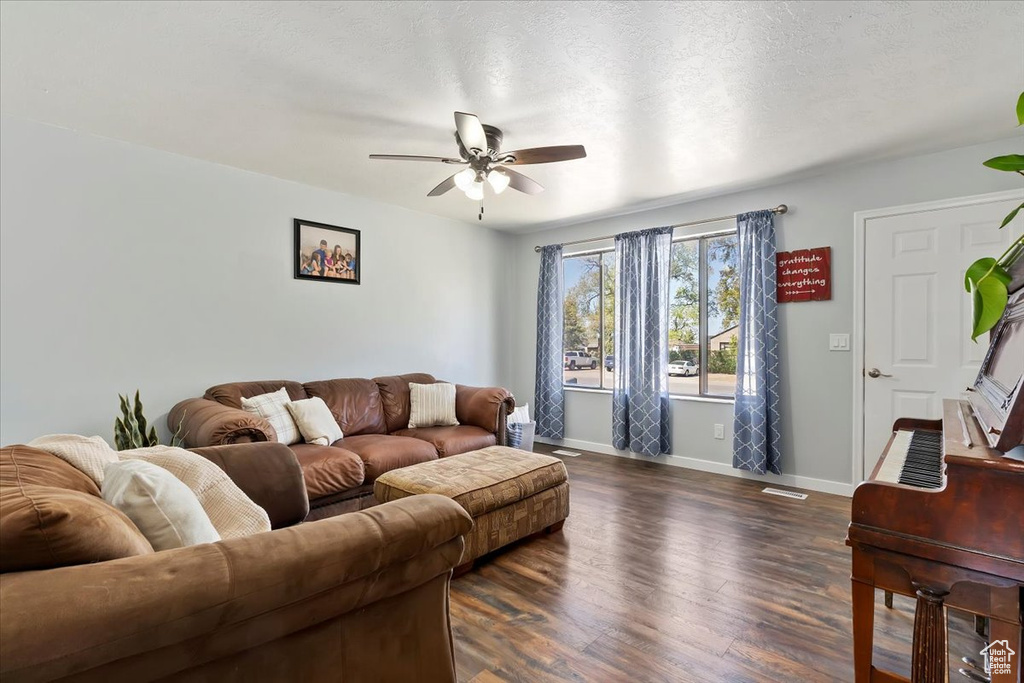 Living area with ceiling fan, visible vents, baseboards, and dark wood-type flooring