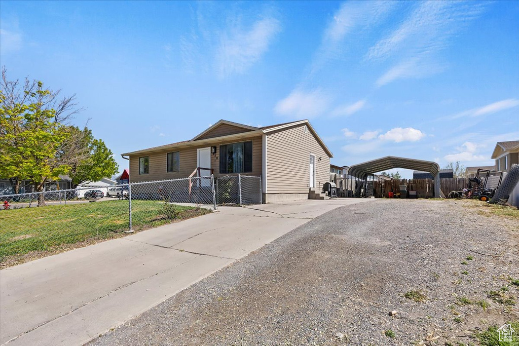 View of front of property with concrete driveway, a front lawn, fence private yard, and a carport
