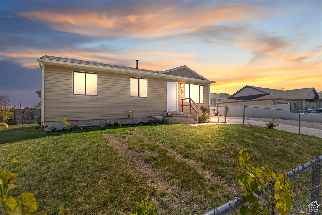 View of front of home with a lawn and fence