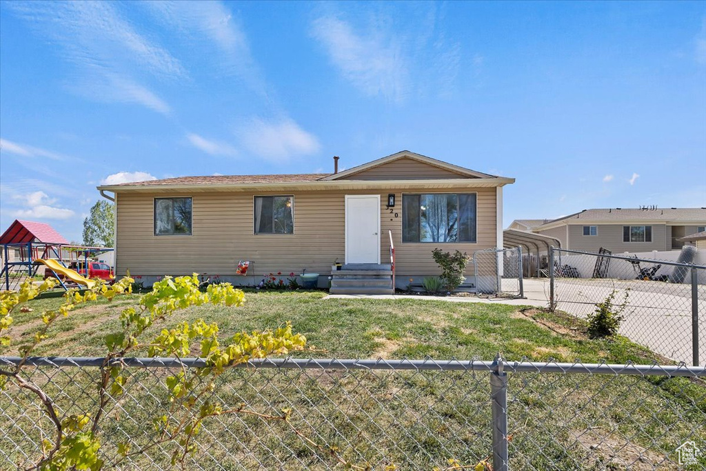 View of front of home featuring a fenced backyard, a front lawn, a playground, and a carport