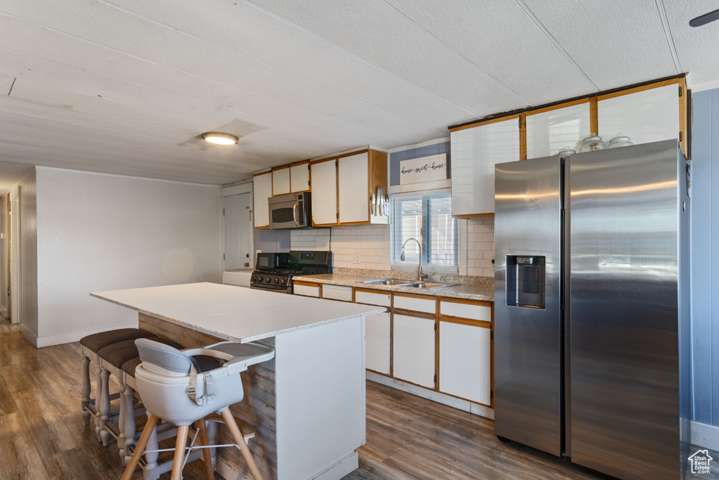 Kitchen featuring light countertops, appliances with stainless steel finishes, a sink, and dark wood finished floors