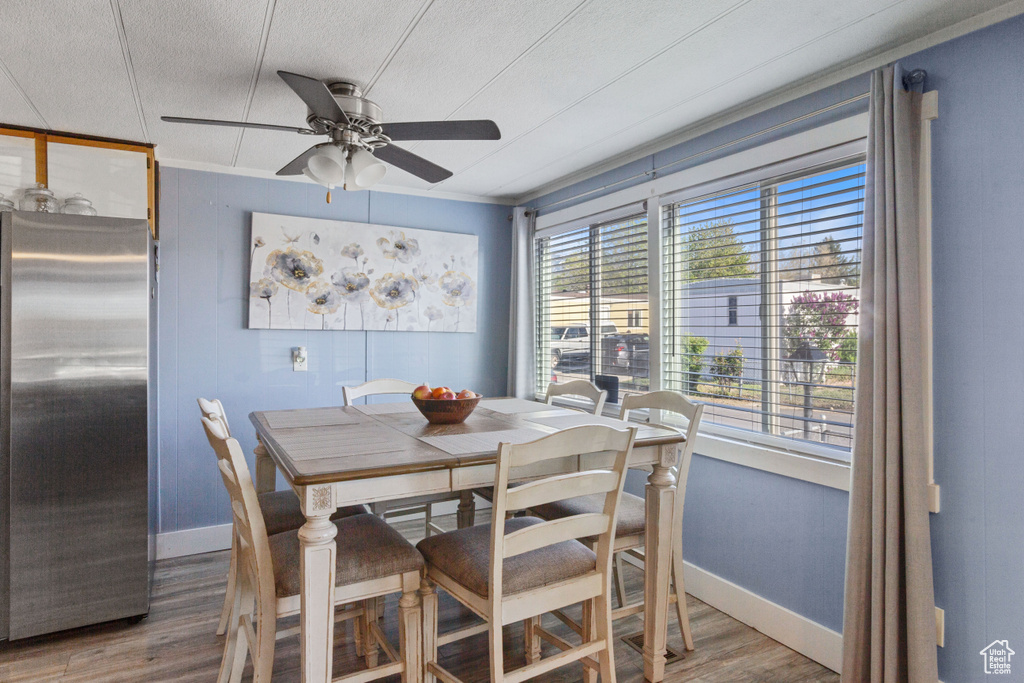 Dining space with baseboards, a ceiling fan, a textured ceiling, and wood finished floors