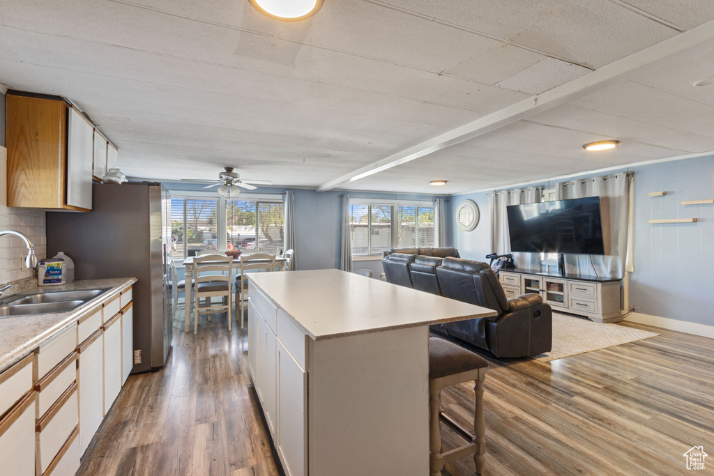Kitchen with a kitchen breakfast bar, a kitchen island, a sink, dark wood-style floors, and open floor plan