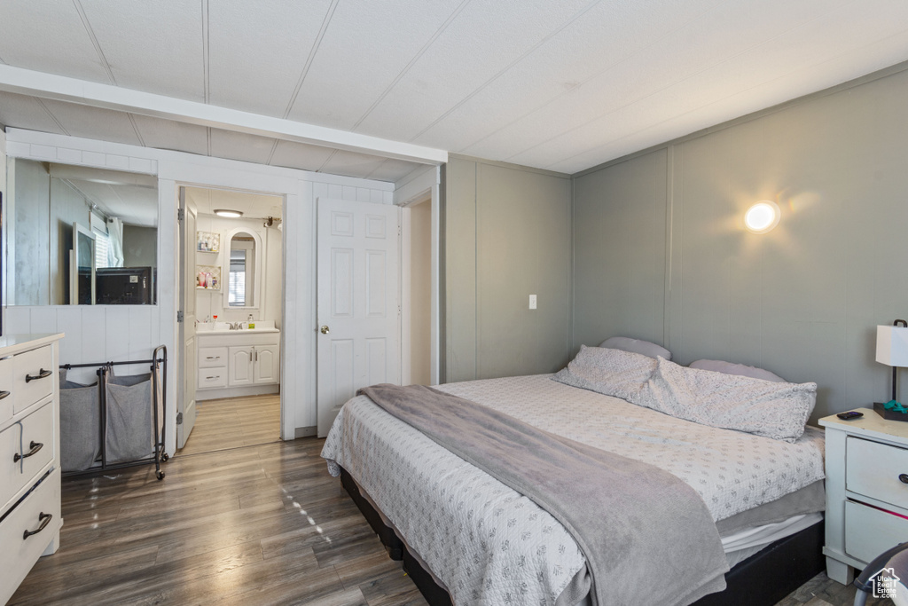 Bedroom with connected bathroom and dark wood-style floors