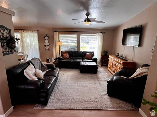 Living area with baseboards, ceiling fan, and wood finished floors
