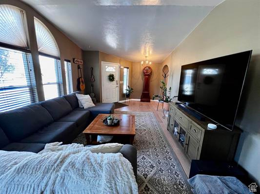 Living area featuring a healthy amount of sunlight, baseboards, wood finished floors, and lofted ceiling