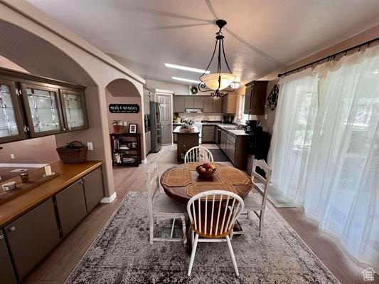 Dining area featuring arched walkways, decorative columns, and light wood-style flooring