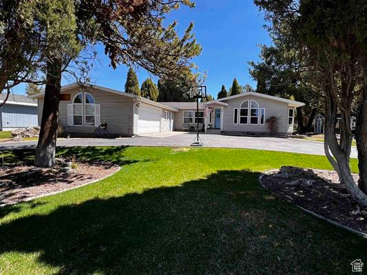 View of front of property featuring concrete driveway, an attached garage, and a front yard
