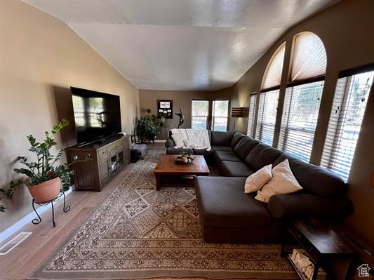 Living area featuring visible vents, light wood finished floors, and lofted ceiling