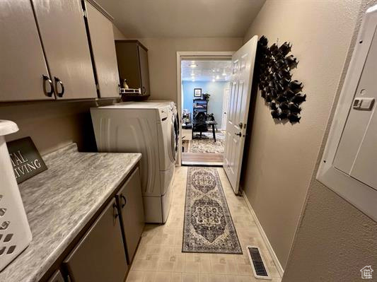 Washroom featuring cabinet space, baseboards, visible vents, and washer and clothes dryer