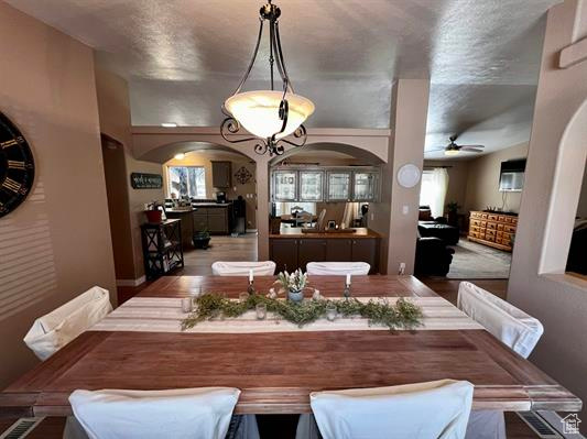 Dining area featuring arched walkways and a ceiling fan
