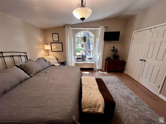 Bedroom with a closet, baseboards, vaulted ceiling, and wood finished floors