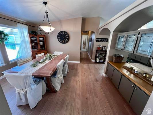 Dining space featuring baseboards, arched walkways, and wood finished floors