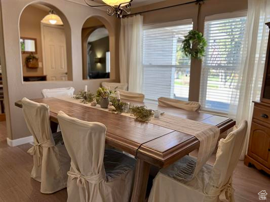 Dining room with light wood-type flooring, arched walkways, baseboards, and a wealth of natural light