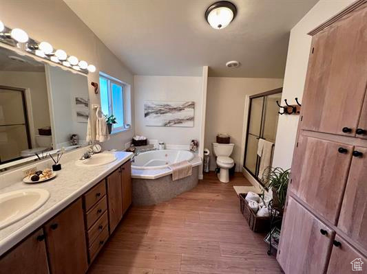 Bathroom featuring a sink, a bath, a stall shower, and wood finished floors