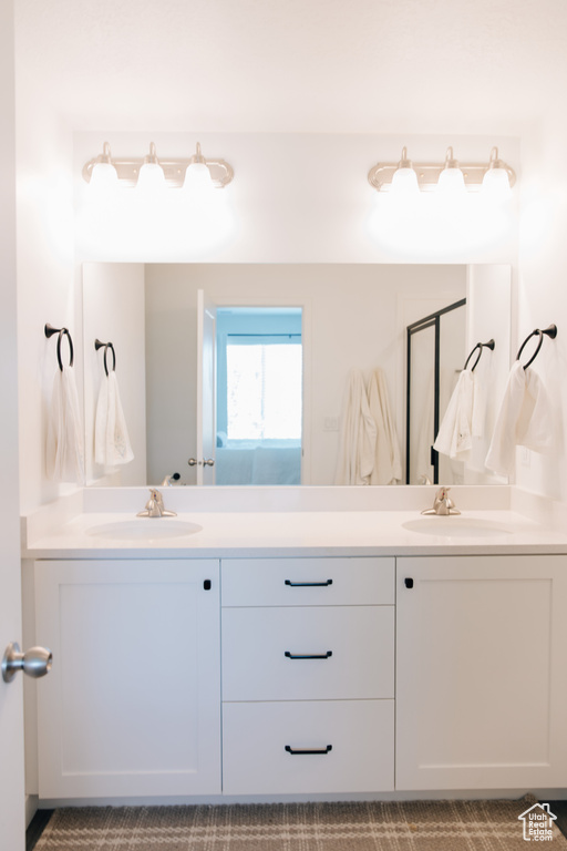 Full bath with a sink, a shower stall, and double vanity