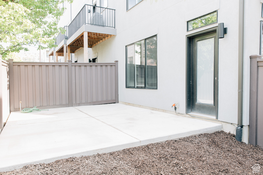 View of patio with fence and a balcony