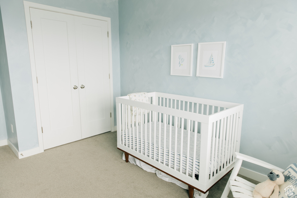 Bedroom with a crib, carpet, and a closet