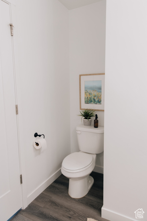 Bathroom with baseboards, wood finished floors, and toilet