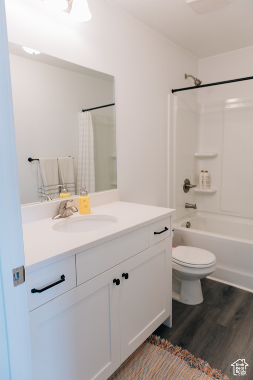 Full bathroom with vanity, shower / tub combo with curtain, wood finished floors, and toilet