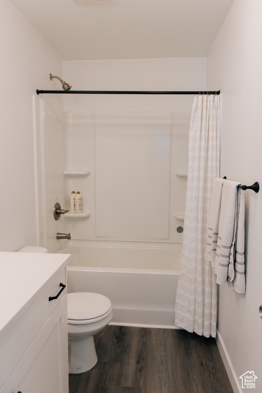 Bathroom featuring vanity, shower / bath combo, toilet, and wood finished floors