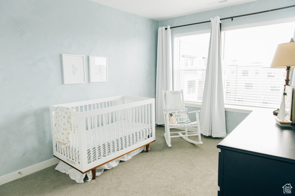 Carpeted bedroom featuring a nursery area