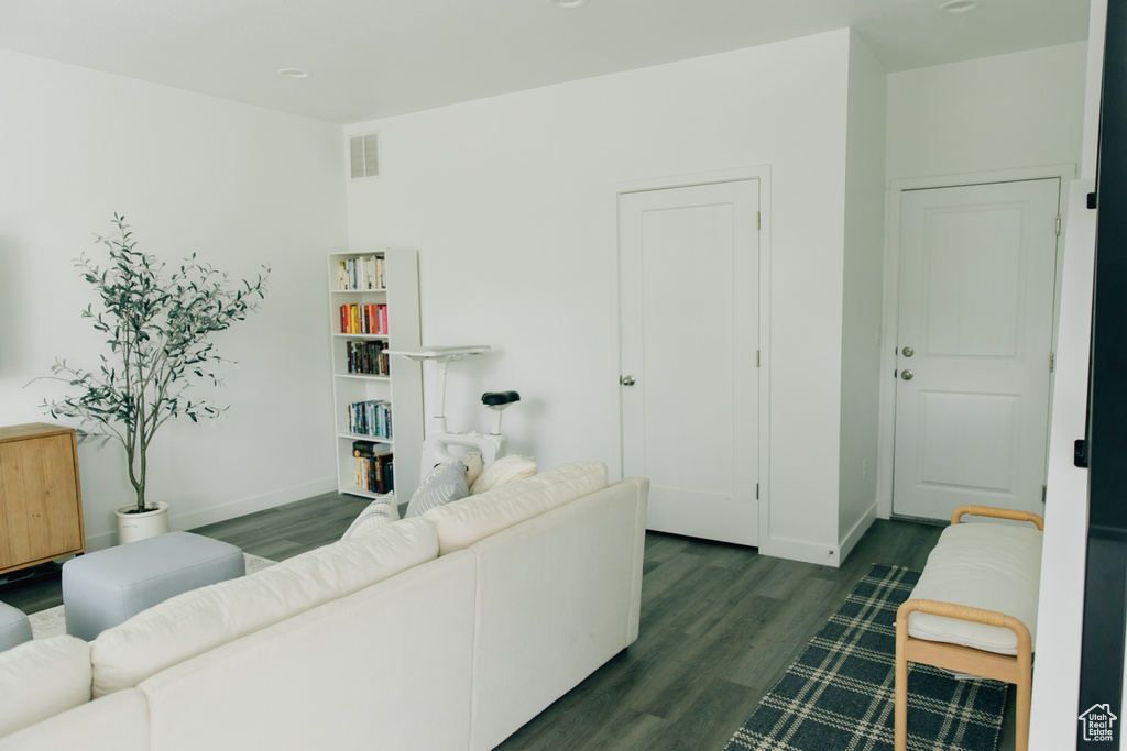Living room featuring dark wood-type flooring, baseboards, and visible vents