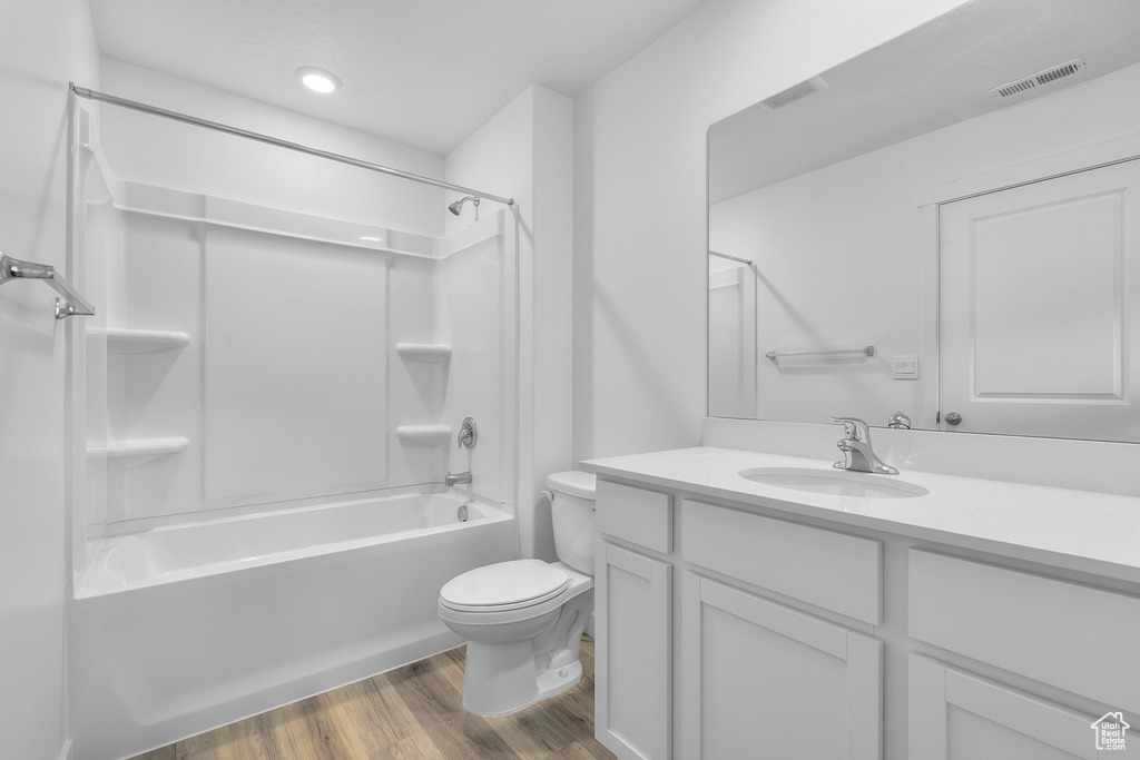 Full bathroom with vanity, toilet, shower / washtub combination, wood finished floors, and visible vents