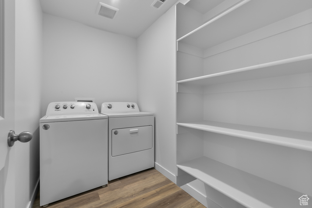 Laundry area with independent washer and dryer, laundry area, visible vents, and wood finished floors
