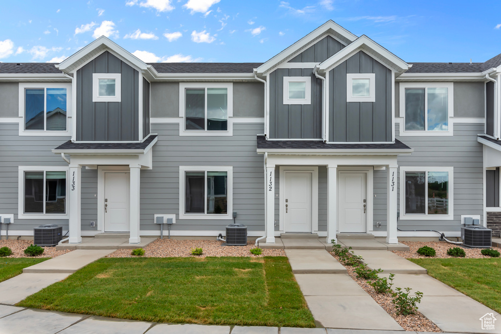 Multi unit property featuring board and batten siding, central air condition unit, and a front yard