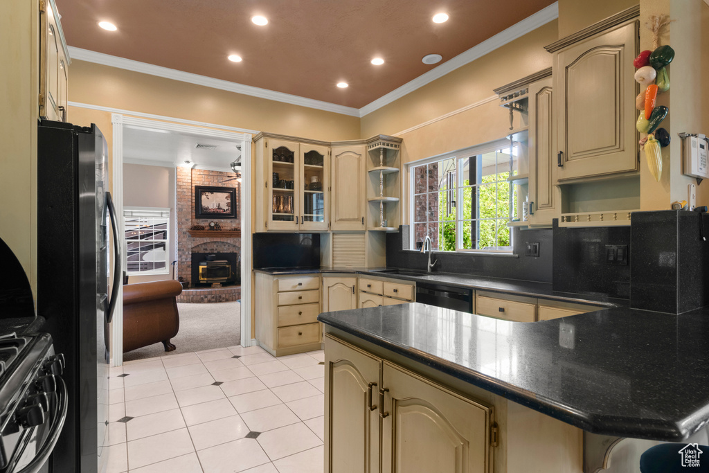 Kitchen featuring freestanding refrigerator, ornamental molding, a peninsula, dark countertops, and cream cabinets